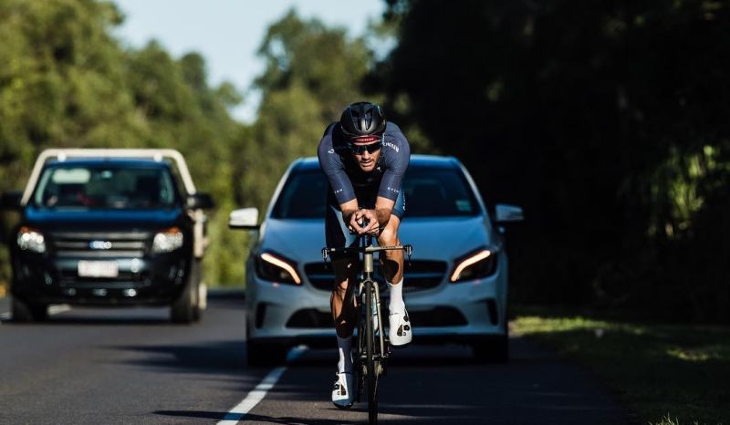 El alemán, entrenando por las carreteras de Queesland con su coche de apoyo.